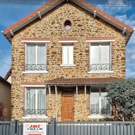 Maison en pierre meulière avec couverture en tuiles terre cuite et zinguerie, panneau de chantier JMC Couverture devant la façade