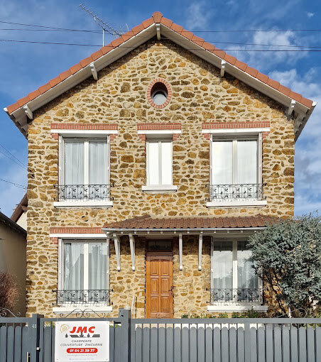 Maison en pierre meulière avec couverture en tuiles terre cuite et zinguerie, panneau de chantier JMC Couverture devant la façade