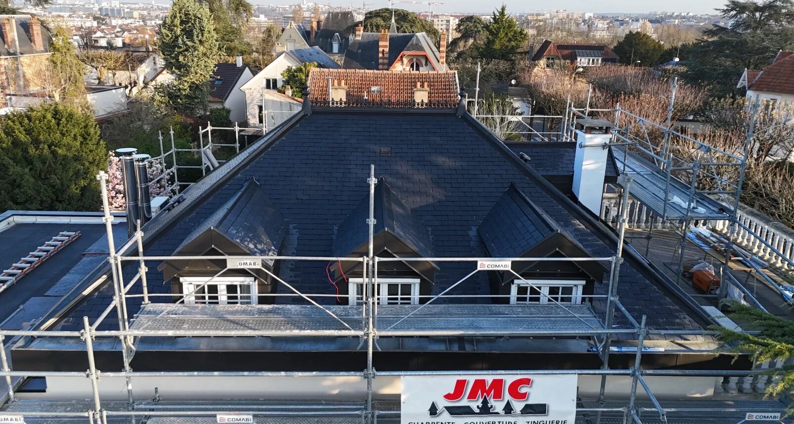Vue aérienne d'une toiture en ardoise avec trois lucarnes habillées de zinc, en finition sous échafaudage par JMC Couverture en Île-de-France